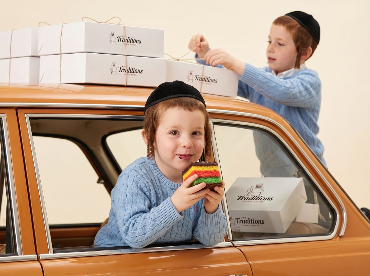 Two boys with bakery boxes on a vintage orange car