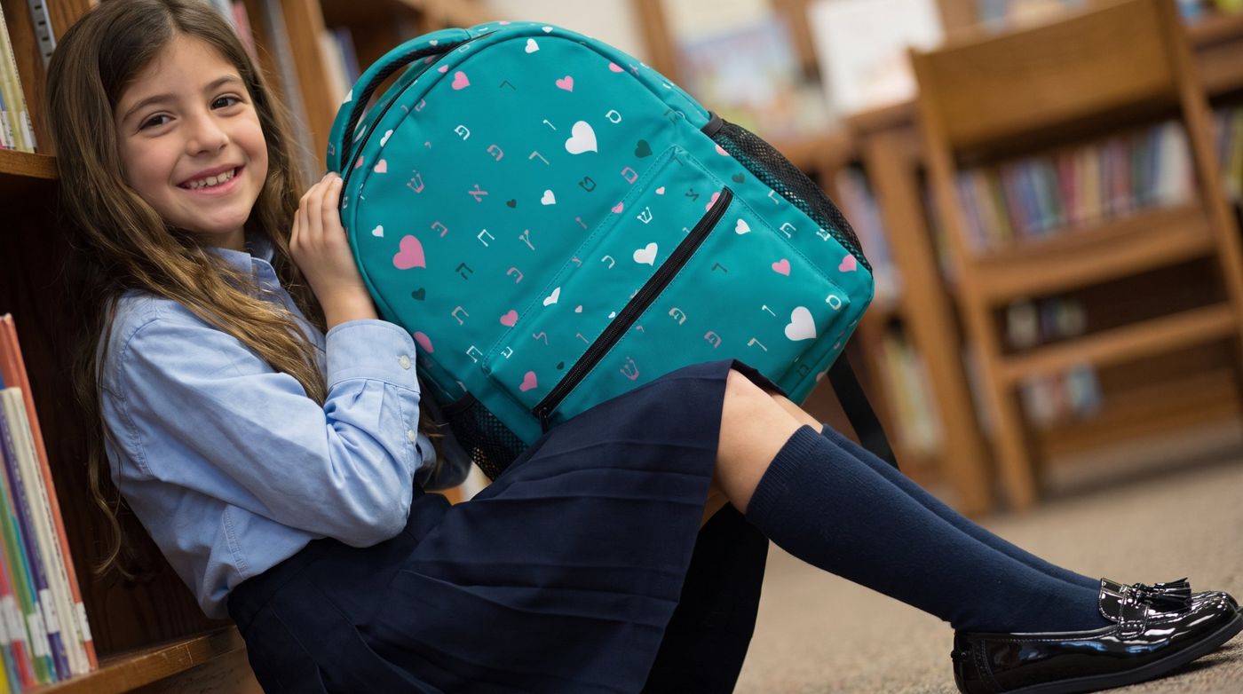 Smiling girl in school uniform hugging a teal backpack